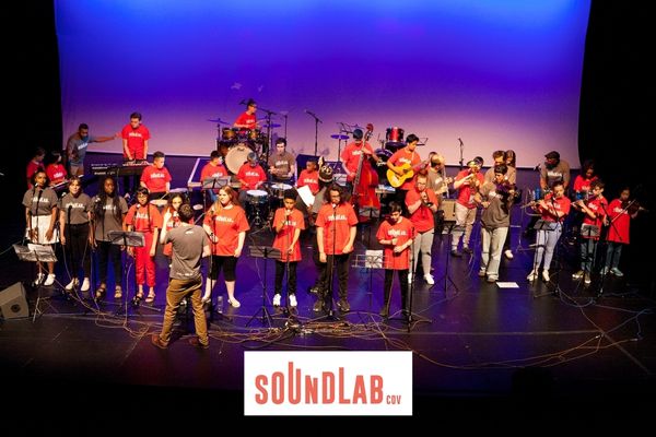 children playing a mixture of instruments on stage